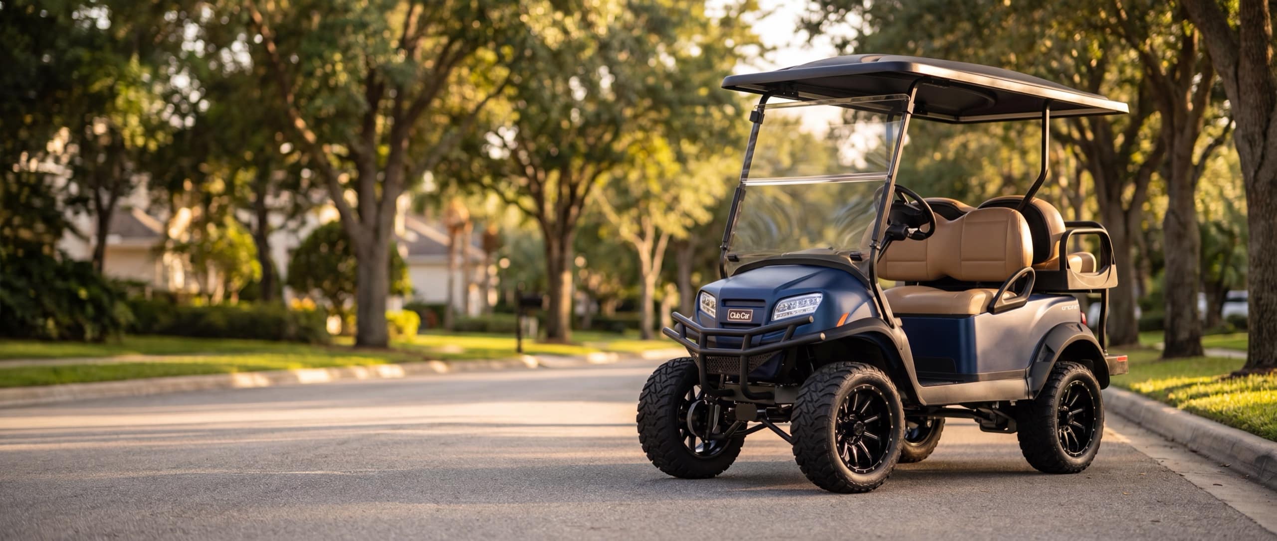 A matte blue-onyx lifted custom Club Car golf cart on a tree-lined street at golden hour