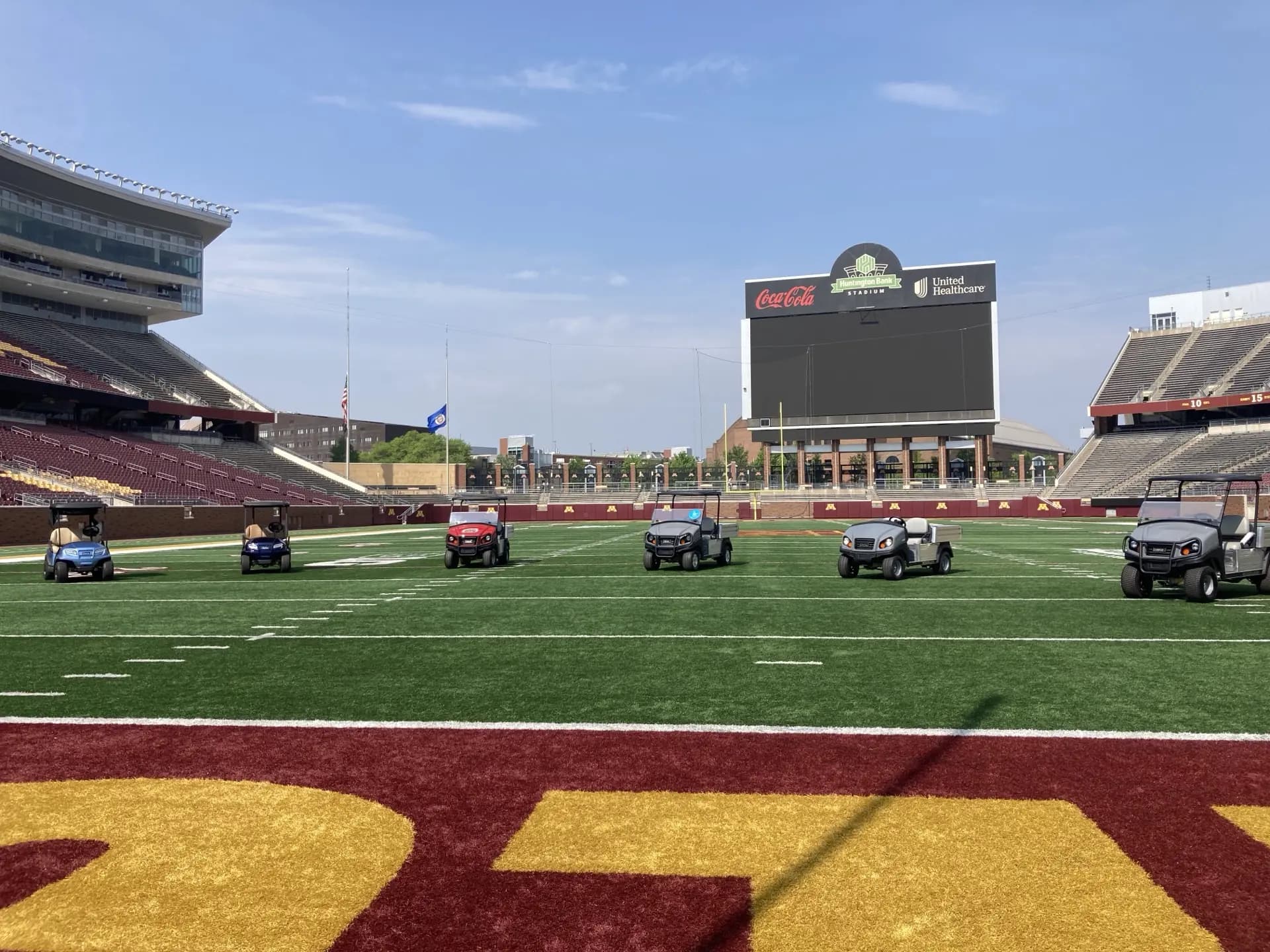 A fleet of Club Car utility and passenger vehicles supplied by MOR Golf and Utility, lined up on the field at Huntington Bank Stadium at the University of Minnesota